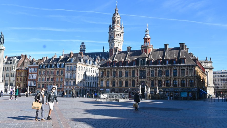 A Lille, un groupe de personnes, dont des personnes portant des masques pour se protéger, traverse la "Grand Place".