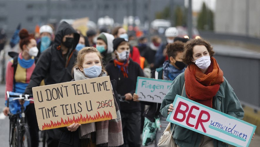 Des manifestants marchent avec des pancartes devant l'aéroport de Berlin lors d'une manifestation de militants du climat.