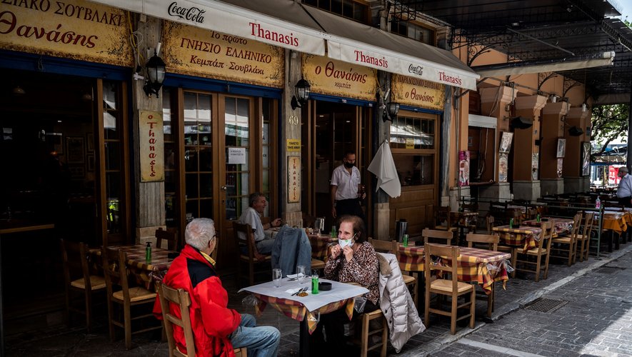 People sit at a restaurant's terrace on Monastiraki square in Athens