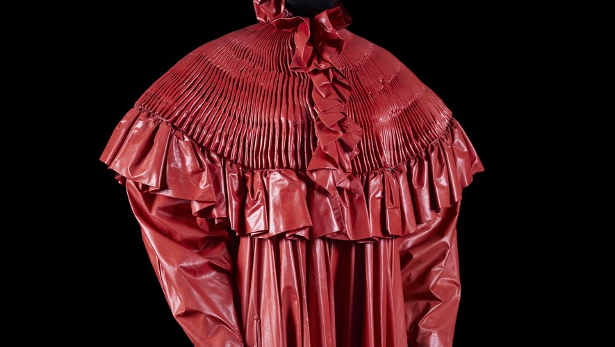 PACO RABANNE - Printemps-été 1985 - Manteau de Cocher - Tissu enduit rouge, ruflette - Griffe blanche, graphisme noir. Estimation : 300 - 500 euros.