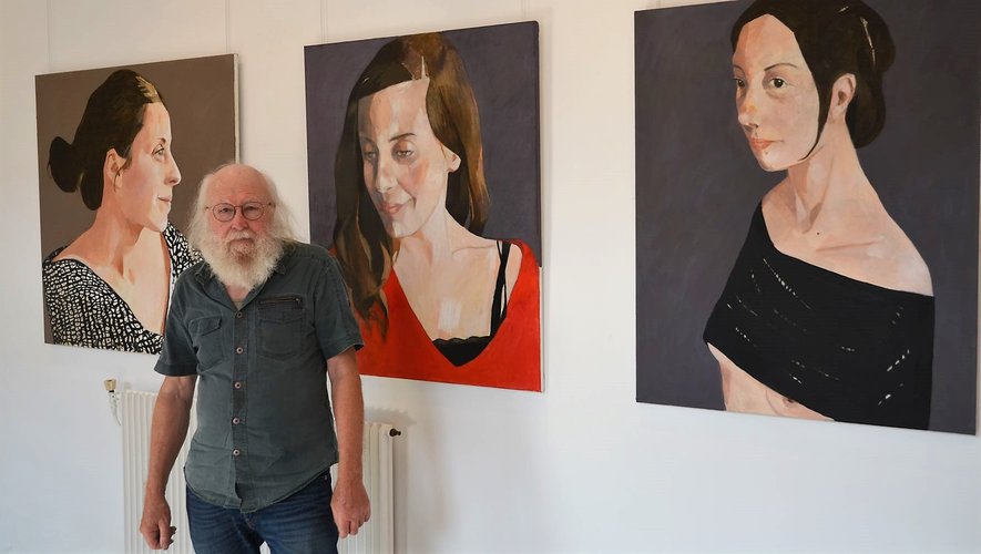 André accueille les visiteurs, devant les portraits peints par Michel Cure  exposés à la galerie Trame d’Arts.