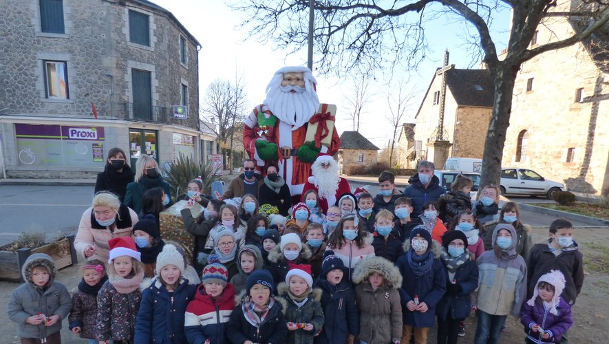 Les écoliers entourés du vrai père Noël et du père Noël géant de la place.