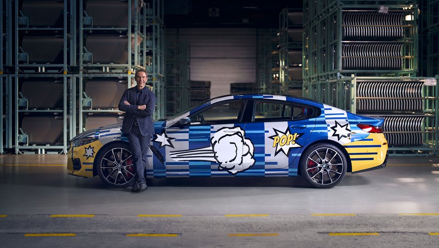 Jeff Koons pose à côté de sa dernière "Art Car" réalisée pour BMW.
