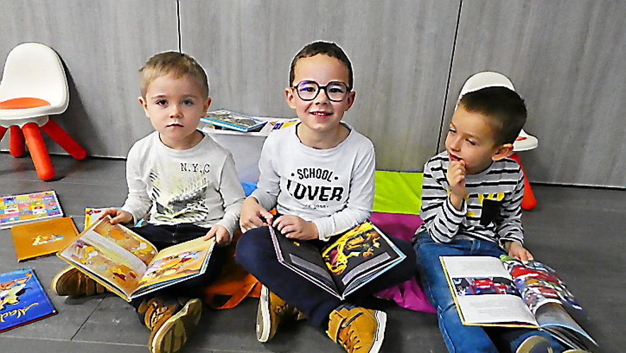 Trois enfants de l’accueil de loisirs plongés dans la lecture.