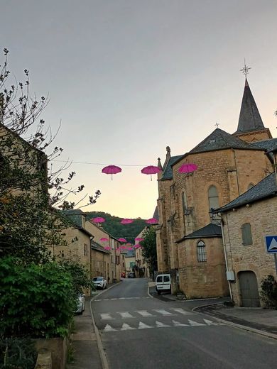 Les rues de Sévérac-l’Eglise ornéesde parapluies roses.