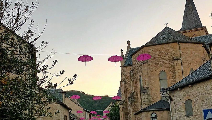 Les rues de Sévérac-l’Eglise ornéesde parapluies roses.