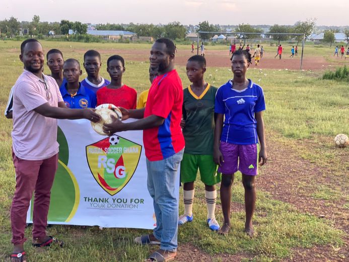 Le coach Capito de l’équipe du village de Tolon avec quelques unes des filles de son équipe et la banderole que RSG a fait faire, là-bas, pour remercier les dons aveyronnais.