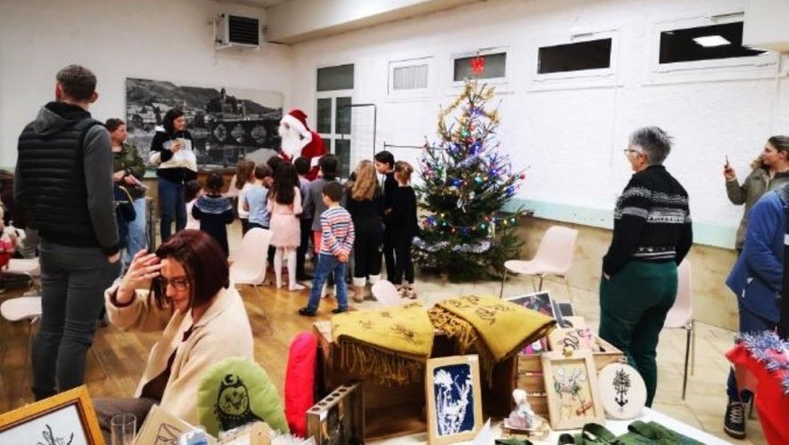Le père Noël, entouré des enfants, effectue la distribution des cadeaux.